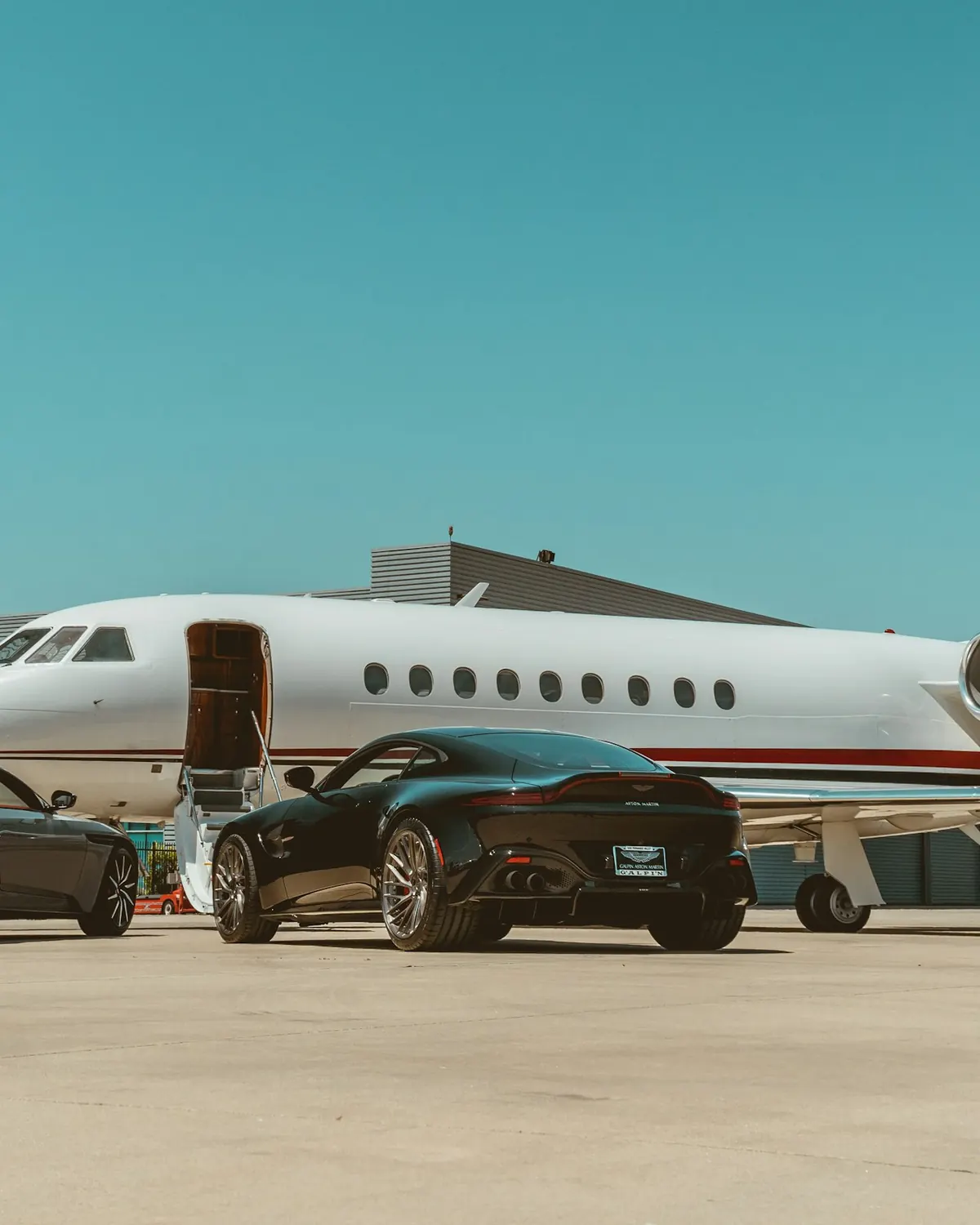 Business jet parked on the ramp with two cars beside the stairs