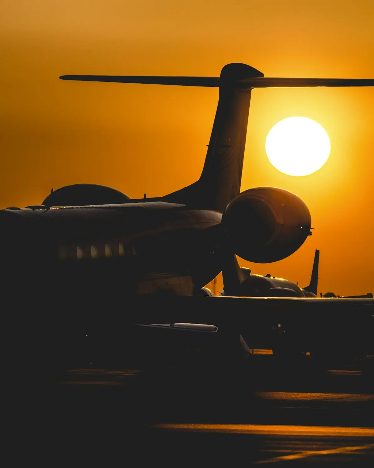 Silhouette of a business jet against a low sun on the runway