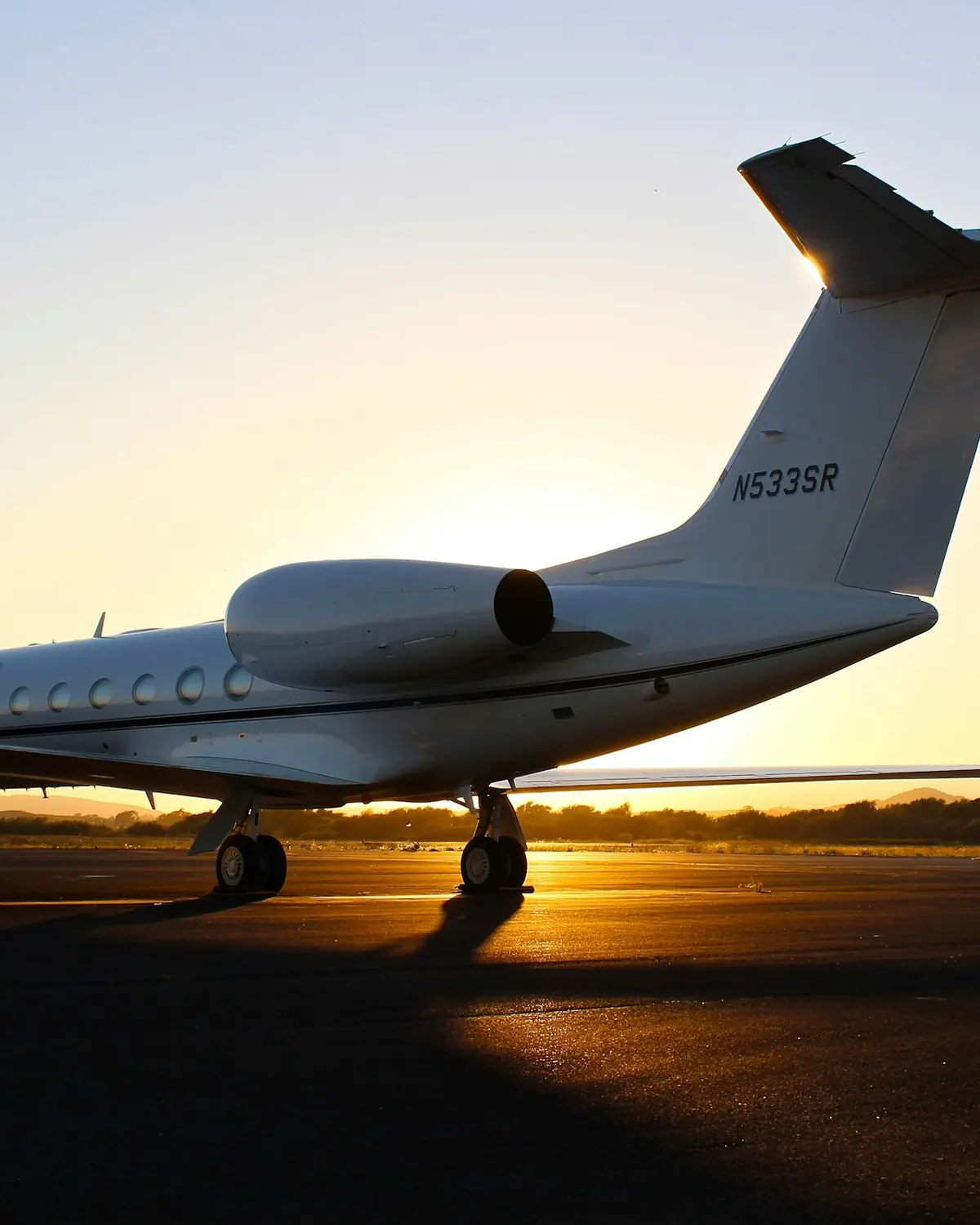 Business jet silhouetted against an orange sunset sky